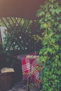 Opened books and red and white plaid on table of the pergola with evening sun