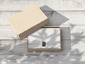 Opened cardboard Gift Box Mockup with white wrapping paper and sticker on the white wooden table outdoor
