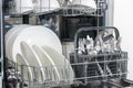 Opened dishwasher machine with clean tableware, white porcelain plates. Convenient modern technologies in the kitchen Royalty Free Stock Photo