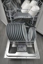 Opened domestic dishwasher with cleaned dishware