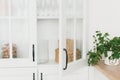 Opened door of white glass cabinet with clean dishes and decor. Scandinavian style kitchen interior. Royalty Free Stock Photo