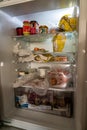 Opened and filled refrigerator in kitchen