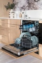 Opened full loaded dishwasher machine in contemporary kitchen