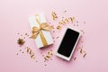 Opened gift box with gold ribbon and smartphone on color background, top view. Blank open box packaging mockup Royalty Free Stock Photo