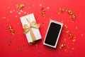 Opened gift box with gold ribbon and smartphone on color background, top view. Blank open box packaging mockup Royalty Free Stock Photo