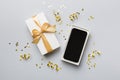 Opened gift box with gold ribbon and smartphone on color background, top view. Blank open box packaging mockup Royalty Free Stock Photo