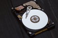 Opened hard drive from the computer on dark wooden background. Art shooting. Royalty Free Stock Photo