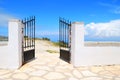 Opened iron gate in a white wall with blue sky