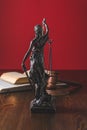 opened juridical books with lady justice statue on wooden table,