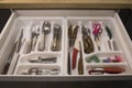 Opened kitchen drawer with a tray and cutlery inside. Grey front of the drawer, white inside, handless design