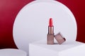 Opened lipstick on white props on red background