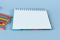 Opened notebook on blue background with colored pencils. Royalty Free Stock Photo