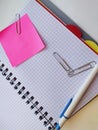 Opened notebook, pink note paper, several paper clips and a white pen Royalty Free Stock Photo