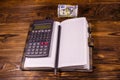 Opened notepad, one hundred dollar banknotes, scientific calculator and pencil on wooden table Royalty Free Stock Photo