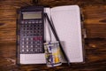 Opened notepad, one hundred dollar banknotes, scientific calculator and pencil on wooden table. Top view Royalty Free Stock Photo