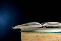 Opened old book on stack of books, dark background Royalty Free Stock Photo