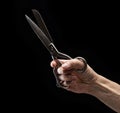 Opened old metal fabric scissors in a man's hand on a black background