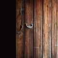 Opened old weathered wooden door with polished metal handle, steel latch and wooden bolt hanging on a string