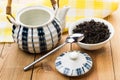 Opened porcelain teapot, bowl with dry black tea and teaspoon