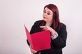 Opened red folder held by redheaded young professional woman pointing at file folder