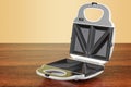 Opened sandwich maker on the wooden table. 3D rendering