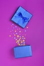 Opened shiny classic blue gift box with satin bow and magic confetti in the shape of stars as attributes of part Royalty Free Stock Photo