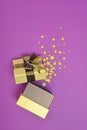 Opened shiny classic golden gift box with brown satin bow and magic confetti in the shape of stars as attributes of party Royalty Free Stock Photo