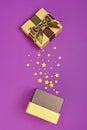 Opened shiny classic golden gift box with brown satin bow and magic confetti in the shape of stars as attributes of party Royalty Free Stock Photo