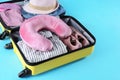 Opened suitcase with travel pillow and clothes on blue background, above view Royalty Free Stock Photo