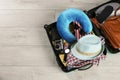 Opened suitcase with travel pillow and clothes on wooden floor. Space for text Royalty Free Stock Photo