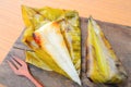 Opened Thai dessert sticky rice wrapped in banana leaf on wood background Royalty Free Stock Photo