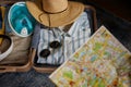 Opened travel suitcase with clothes and paper map selective focus