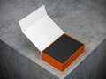 Opened white box with orange interior part and black box inside on concrete table