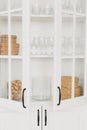 Opened white glass cabinet with clean dishes and decor. Organization of storage in kitchen. Royalty Free Stock Photo