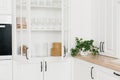 Opened white glass cabinet with clean dishes and decor. Scandinavian style kitchen interior. Organization of storage in kitchen. Royalty Free Stock Photo