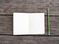 Opened white page of blank notepad notebook and green pencil on wood texture background Royalty Free Stock Photo