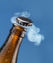 Opening beer bottle on blue background. Gas cloud going out of the beer bottle blowing the cap Royalty Free Stock Photo
