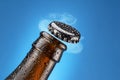 Opening beer bottle on blue background. Gas cloud going out of the beer bottle blowing the cap Royalty Free Stock Photo