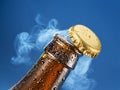 Opening beer bottle on blue background. Gas cloud going out of the beer bottle blowing the cap Royalty Free Stock Photo