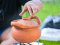 Opening the cap of clay pot with hand. Cooking process on tourist camp.