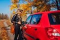 Opening car door. Woman opens red car with key on autumn road Royalty Free Stock Photo