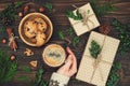 Opening Christmas present. Woman's hands holding decorated gift box on rustic wooden table. Ideal morning breakfast. Royalty Free Stock Photo