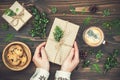 Opening Christmas present. Womans hands holding decorated gift box on rustic wooden table. Overhead, flat lay, top view Royalty Free Stock Photo