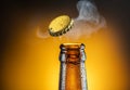 Opening of cold beer bottle - gas output and bottle cap in the air. Isolated on a yellow background Royalty Free Stock Photo