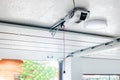 Opening door and automatic garage door opener electric engine gear mounted on ceiling with emergency cord. Double place empty Royalty Free Stock Photo