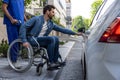 Dark-haired man on a wheelchair opening a car door Royalty Free Stock Photo