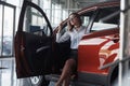 Opening the door. Woman in eyewear, black skirt and white shirt sits in the red automobile