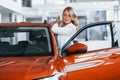 Opening the door. Woman in formal clothes is indoors in the autosalon