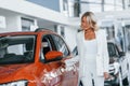 Opening the door. Woman in formal clothes is indoors in the autosalon