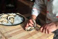 Opening the hollow and flat oysters. Chef opens oysters in the restaurant. Royalty Free Stock Photo